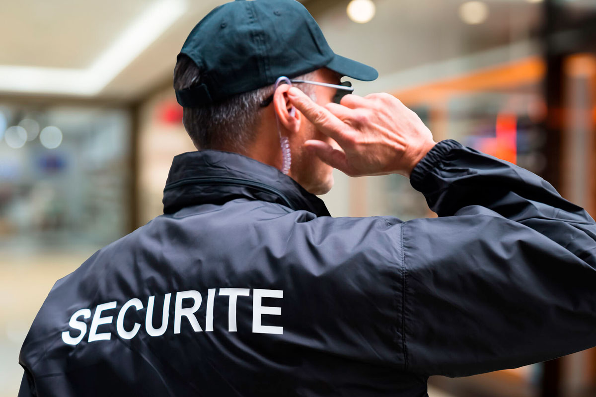Formation MAC APS à Paris, agent de sécurité avec une casquette et une oreillette de dos avec sur son blouson la marque SECURITE